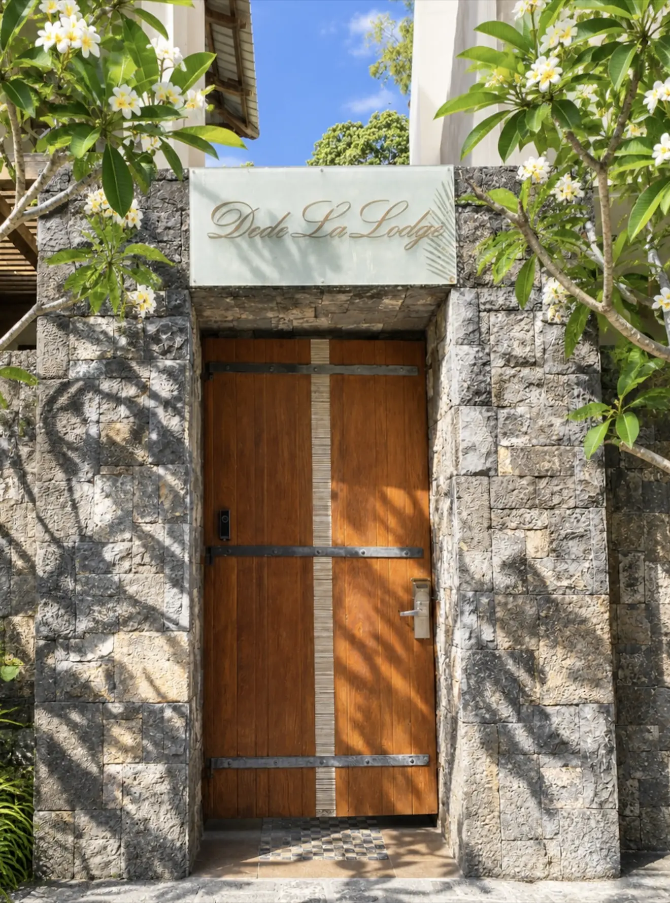 The front door of the lodge, framed in stone with frangipani overhead